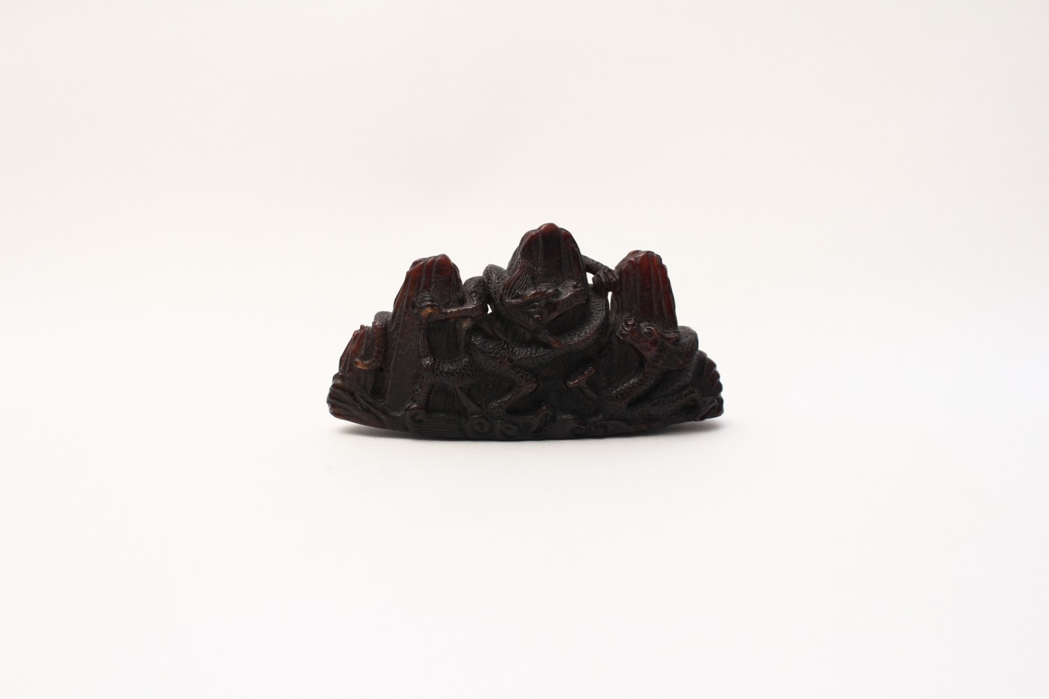 An amber brush rest depicting a dragon amidst mountains