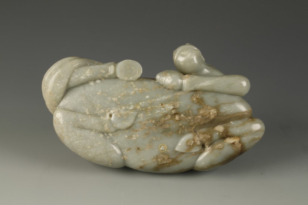 A celadon jade reclining horse with brown mottling (late Ming dynasty, 17th century)